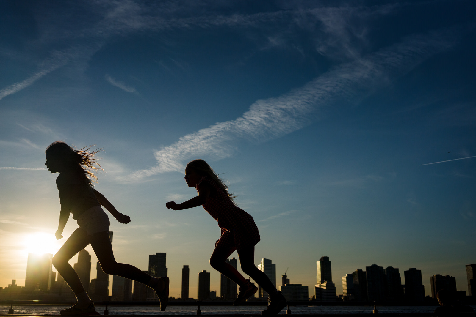Two kids silhouette running with NY as their backdrop