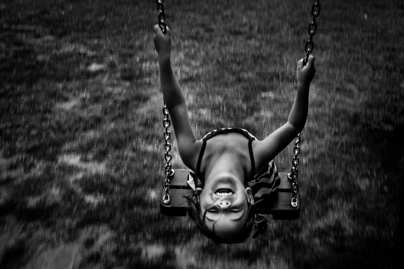 Little girl in a swing smiling looking up