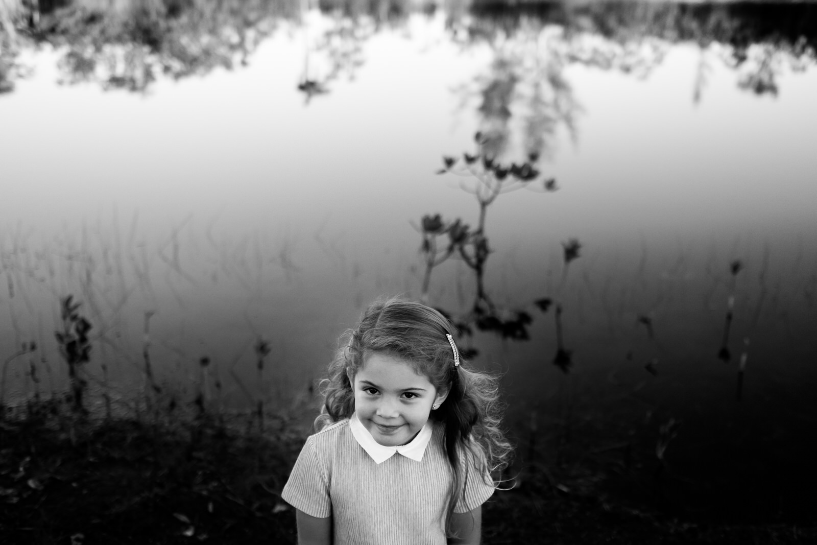 Little kid's portrait looking at the camera with a lake as backdrop