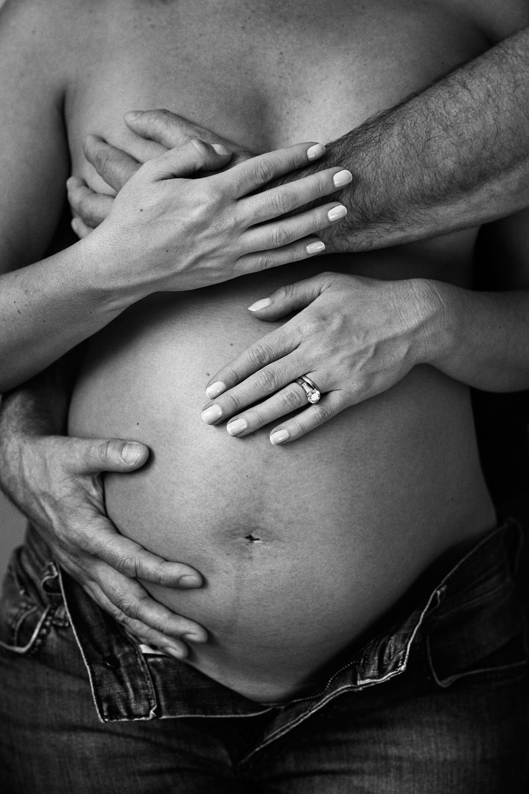 Pregnant woman's belly hugged by father's hand